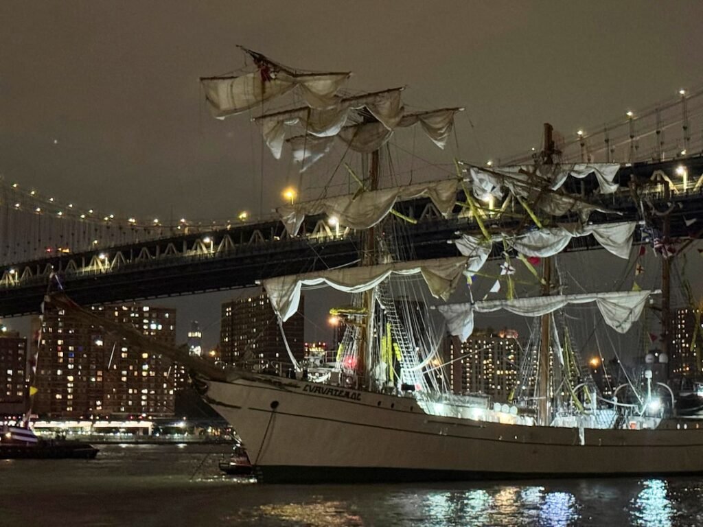 Detailed night view of the Mexican Navy's training ship Cuauhtémoc with its sails and rigging, illuminated against the backdrop of the Brooklyn Bridge and city lights, prior to the May 17, 2025 incident.
