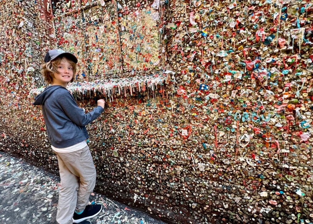 Child visiting the Seattle Gum Wall covered in colorful chewing gum