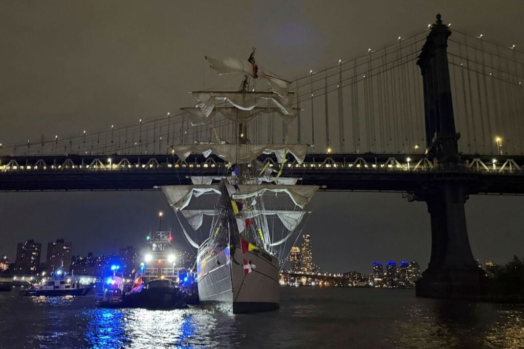 Mexican Navy training ship Cuauhtémoc passing under a lit bridge at night in New York, likely before its collision with the Brooklyn Bridge on May 17, 2025.