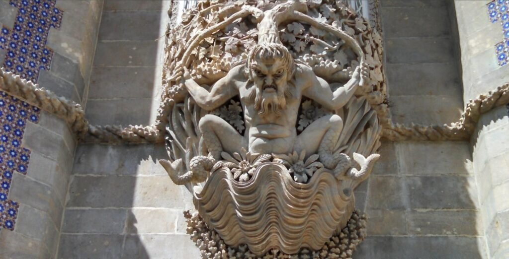 A stone sculpture of a triton-like figure emerging from a large seashell, set into a tiled wall.