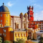 Pena Palace, a vibrant Romanticist castle atop Sintra's hills, showcases eclectic architecture and stunning views over lush Portuguese landscapes.