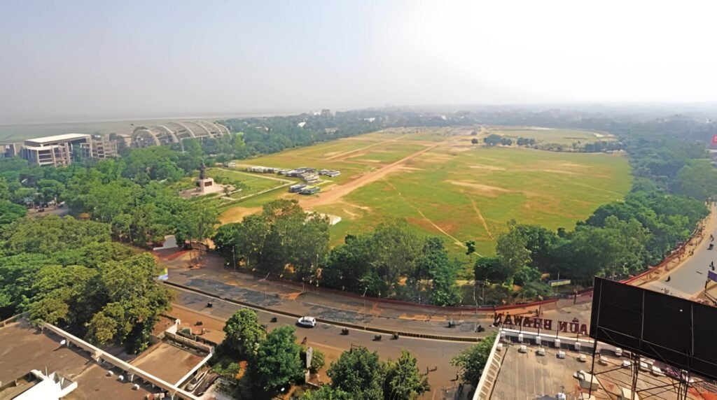 Gandhi Maidan in Patna, India, showing the expansive green field surrounded by trees, roads, and nearby urban buildings under a hazy sky.