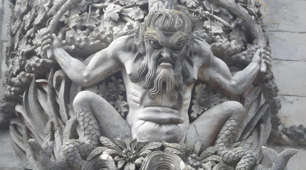 Close-up of the stone Triton sculpture, the iconic guardian of the Triton Gate Pena Palace in Sintra, featuring its fierce expression and intricate marine details.