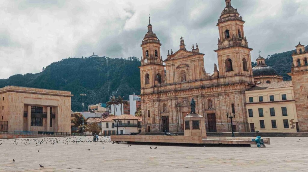 Plaza Bolívar in Bogotá, Colombia, featuring the Primatial Cathedral, Simón Bolívar statue, and surrounding colonial architecture against a mountainous backdrop.