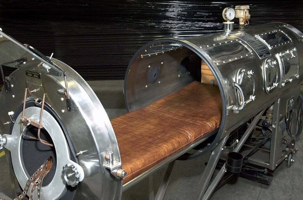 Close-up of a vintage iron lung machine with an open door revealing the leather padding inside, illustrating the device’s size and design.