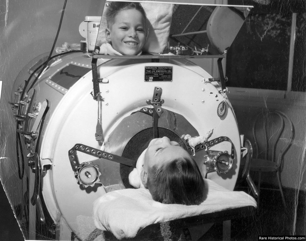 Historic hospital ward filled with rows of iron lungs, nurses caring for polio patients in the 1930s-1950s era.