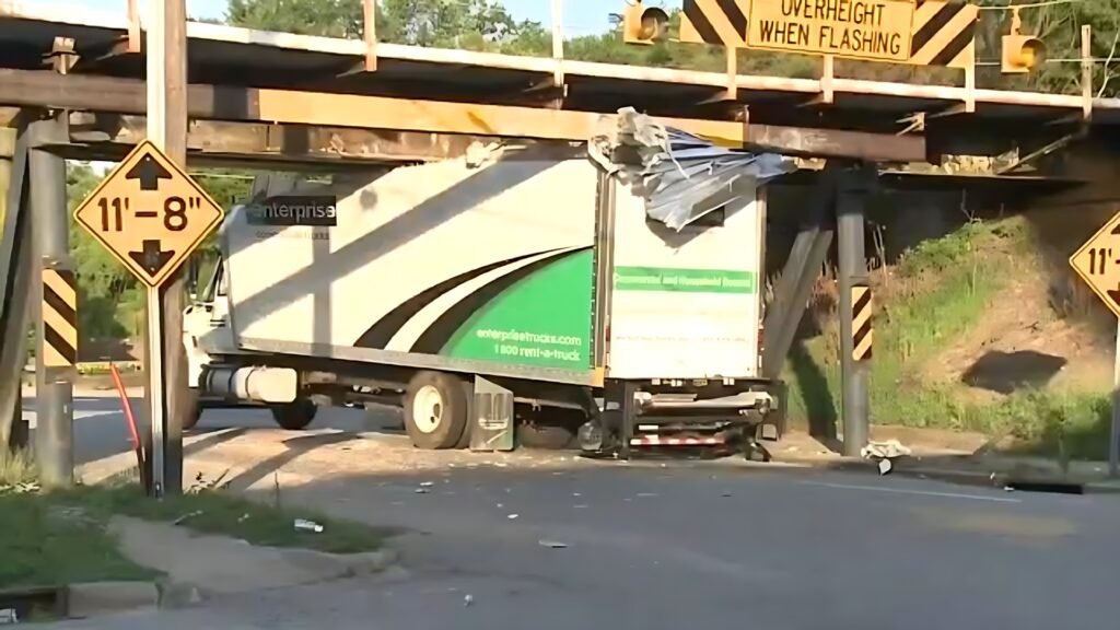 An Enterprise rental truck with its roof torn open after crashing into the infamous 11foot8 Bridge, despite an "11'-8"" clearance sign being visible.
