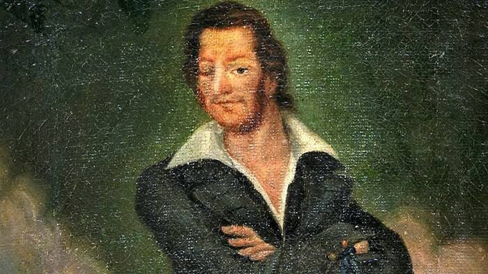 A painting depicts Giorgio Orsolano, a man with reddish-brown hair and a beard, wearing a dark coat and a white shirt open at the collar, against a dark, textured background.