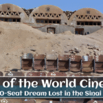 Abandoned cinema seats in front of unique dome-shaped structures, part of the lost desert theater known as the End of the World Cinema.