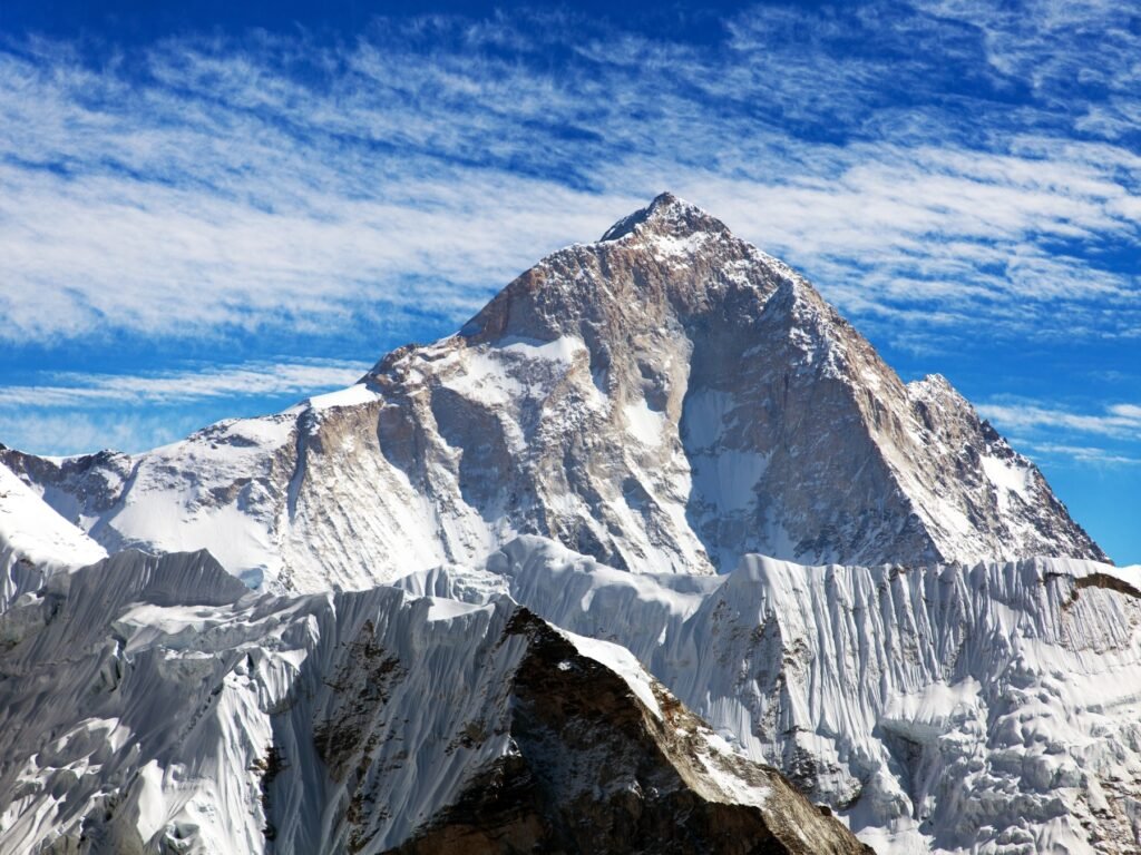 Makalu, the fifth highest mountain on Earth at 8,485 meters, featuring steep rocky and snowy slopes under a bright blue sky, located on the Nepal-China border.