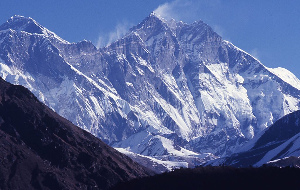 Lhotse, the fourth highest mountain on Earth at 8,516 meters, showing steep rocky and snowy peaks, located on the Nepal-China border under a clear blue sky.