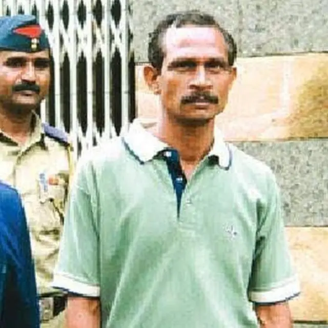 A police custody photo of the person Akku Yadav, a gangster from Nagpur, wearing a green polo shirt and looking at the camera before his death.