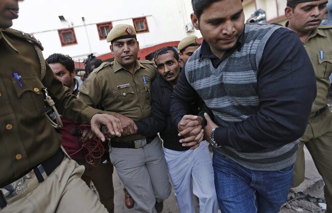 The person Akku Yadav is forcefully escorted by multiple Indian police officers through a chaotic scene, highlighting the turmoil surrounding his criminal history.