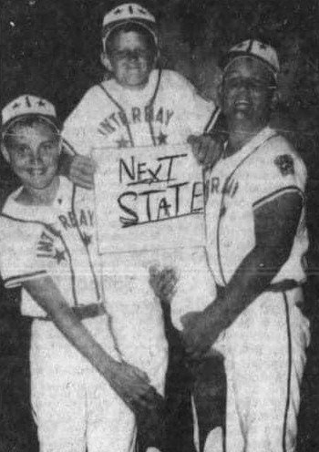 A black and white photo of a young Hulk Hogan (center) and two teammates in their Little League baseball uniforms, holding a sign that reads "Next STATE".