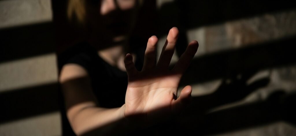 A hand reaching out from shadows, symbolizing the hidden suffering and vulnerability faced by domestic workers behind closed doors.