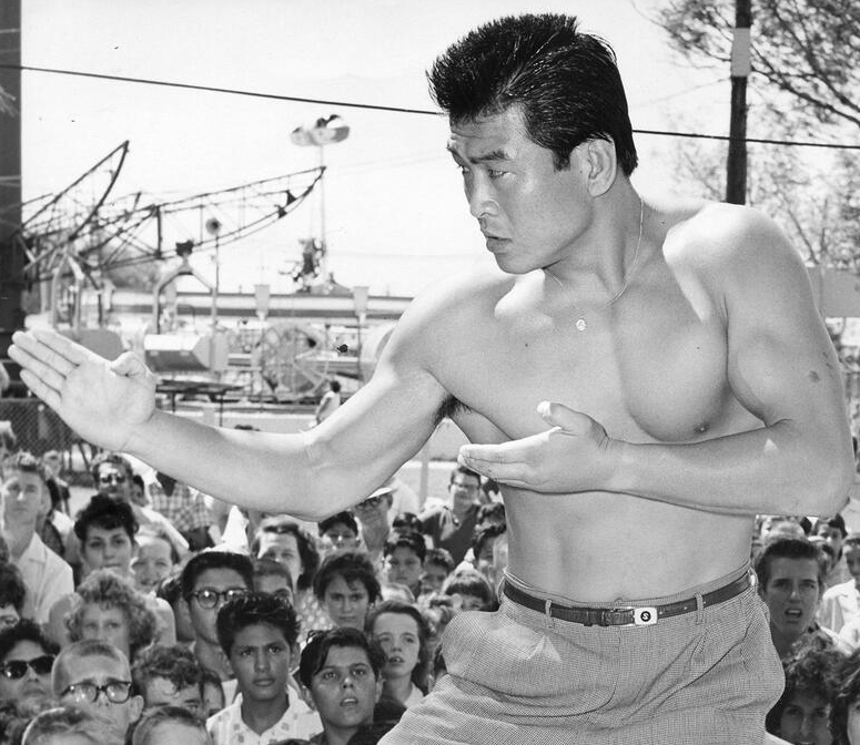 Japanese pro wrestler and trainer Hiro Matsuda, who famously trained Hulk Hogan, demonstrating a karate chop in front of an outdoor crowd.