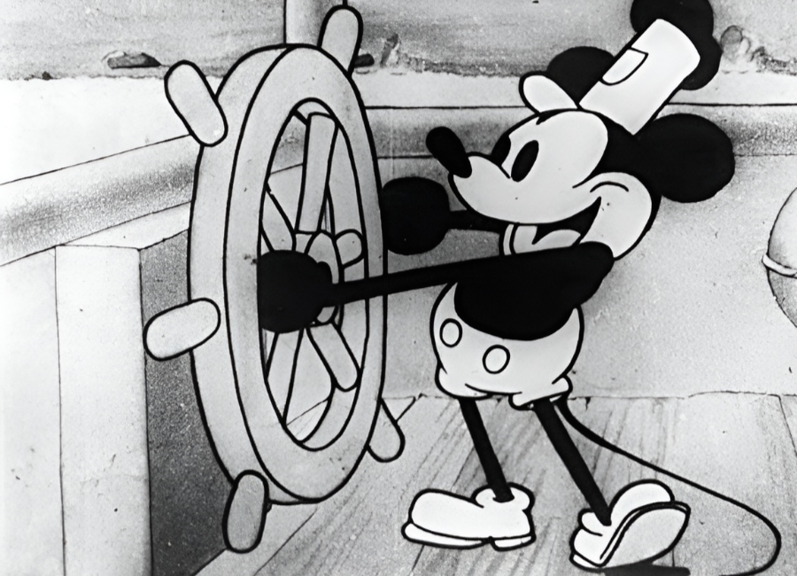 Classic Mickey Mouse from Steamboat Willie steering a ship’s wheel in black-and-white animation.