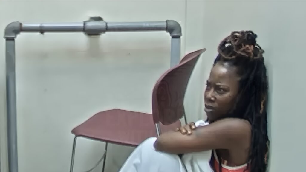 Nicole Michelle Johnson sitting on the floor in a room, looking distressed.