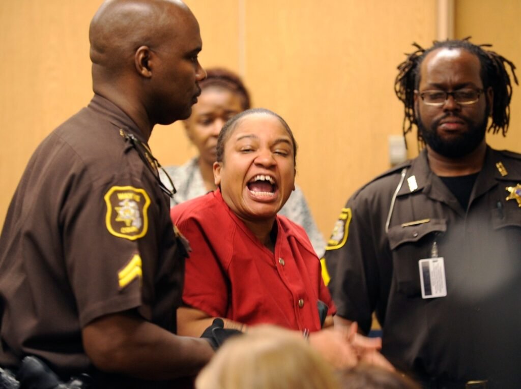 Mitchelle Blair shouting in the courtroom, flanked by two sheriff's deputies, during a hearing for her case.
